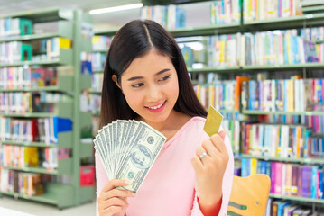 Smiling girl showing platic credit card and holding dollar