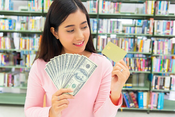 Smiling girl showing platic credit card and holding dollar