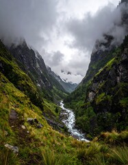 Deep mountain gorge carved by a river, shrouded in clouds