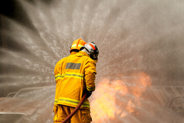 Firefighters spraying water to control extinguish an intense blaze.