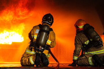 Firefighters spraying water to control extinguish an intense blaze.