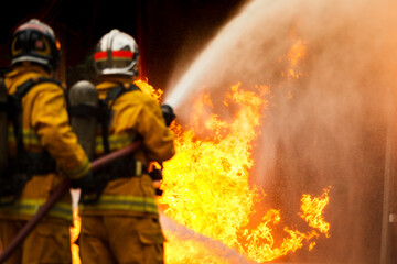 Firefighters spraying water to control extinguish an intense blaze.