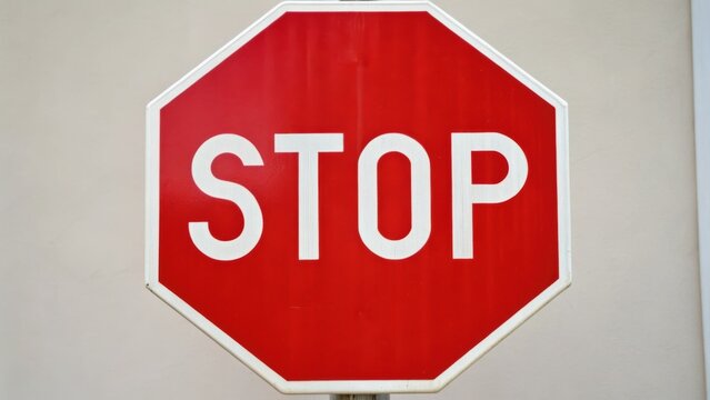 Red octagonal stop sign on a wall, clearly displaying the word "STOP" in white letters.