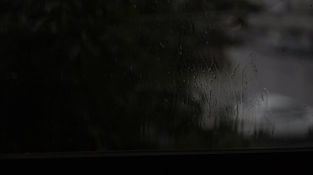 Raindrops Splash On Window Glass, A cinematic film clip of raindrops splashing on window glass, perfect for a melancholic mood film or a soothing rain documentary.