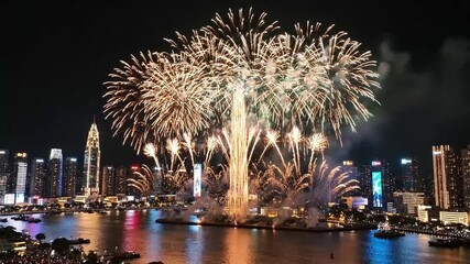 Stunning golden fireworks display illuminating a modern city skyline over the water at night. - Powered by Adobe