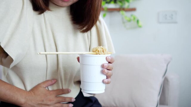 woman burning stomach pain after eating spicy noodles, feeling heartburn, gas, and indigestion. Concept of bloating, stomachache, digestive discomfort, and irritation caused by spicy or heavy foods