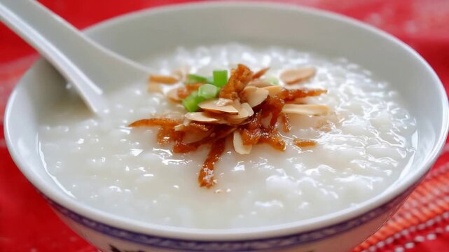 Nourishing Bowl of Comforting Congee with Savory Toppings and Spoon.
