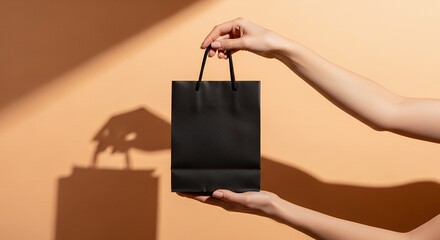Mockup of a hand holding a plain black shopping bag, soft pastel studio background