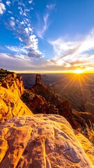 A vibrant sunrise casts a golden glow over a vast canyon landscape, highlighting rock formations and cloudscape