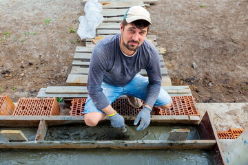 A young handsome man is making a porch for his new private house