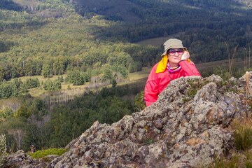 Portrait of a beautiful mature female tourist walking along the rocks in the Ural Mountains on a summer day