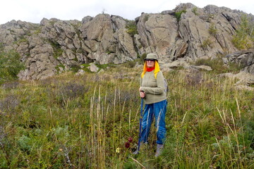 Portrait of a beautiful mature female tourist walking along the rocks in the Ural Mountains on a summer day