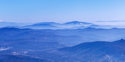 Aerial view of mountain ridges in soft fog and sky. Beautiful white blue peaks Altay mountains fades in distance. Minimal Nature abstract banner, natural winter picturesque scene, panoramic skyline.