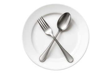 Polished silver fork and spoon crossed diagonally on a plain white round dinner plate, a minimalist and clean composition of simple eating utensils isolated on transparent background