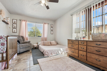 A cozy bedroom with a bed, dresser, chair, and ceiling fan