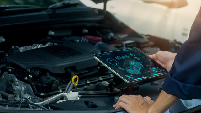 A technician uses a digital tablet to analyze engine data and monitor automotive performance with advanced diagnostic technology. Ideal for smart maintenance, modern vehicle inspection, 