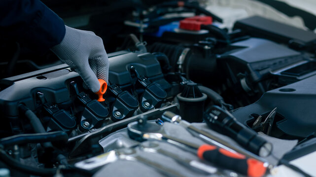 A mechanic wearing protective gloves checks the engine oil dipstick during a vehicle inspection, performing essential maintenance in an automotive workshop. Ideal for car service, repair, 