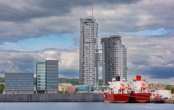 Two red cargo ships and Sea Towers skyscraper at the harbor in Gdynia, Poland