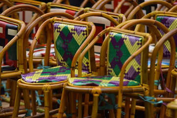 Rows of traditional rattan chairs with colorful patterned cushions, ready for an event or gathering.