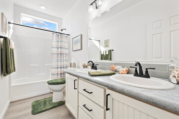 A designed bathroom with two sinks, a toilet, and a bathtub
