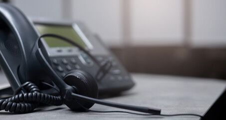 close up black headset with telephone in operation room to communicate with vendor or client for call center and hotline service concept