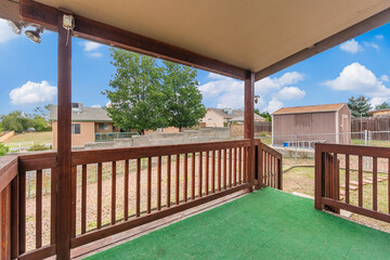 A charming porch featuring a sturdy wooden railing and a vibrant green rug