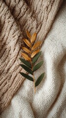 Cozy Autumn Still Life - Textured Knits Embrace a Single Golden Leaf.