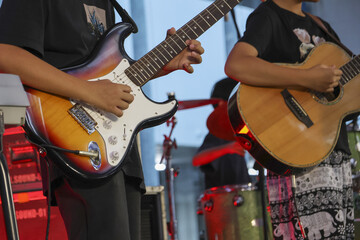 Passionate musician and guitarist from music band playing electric guitar and acoustic guitar. focused live concert performance with two players jamming together on stage