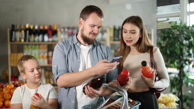 Couple young man and woman buyers with boy scanning qr code for juices in bottle in grocery store