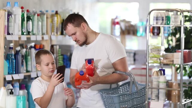 Young man with his son buyers scanning qr code for unclogging gel in household chemicals store