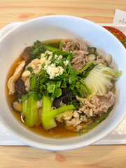 The closed up of Thai noodles. Asian noodle soup with beef meatball with fresh vegetable on wood table.
