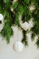 Green fir branches with white paper ornaments and warm led lights hanging