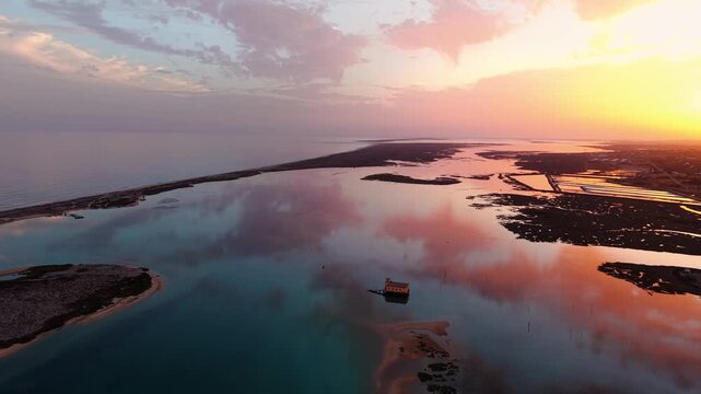 Aerial shot around Fuseta lifeboat station at sunset revealing the Olhao salt pans in the background, Ria Formosa Natural Park, Algarve region, Portugal