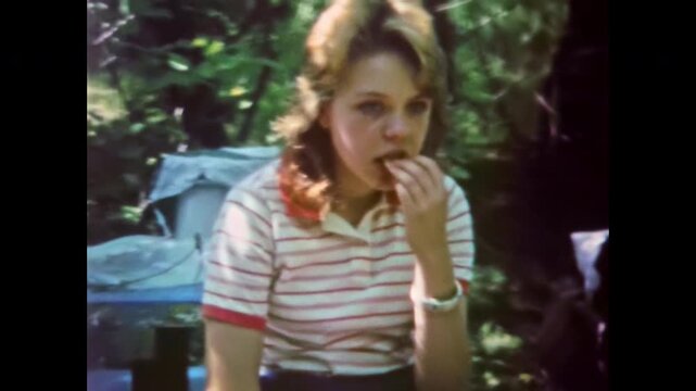 Bored teenage girl portrait at countryside camp on summer vacation. Teenage apathy, melancholy. Teen angst. Summer on bench boredom in nature. Old film. Archival retro 1960s. Vintage archive.