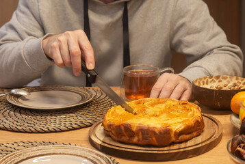 A man cuts a piece of pie while sitting at the dining table. Home food. Tea time