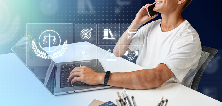 Man working on laptop while talking on phone in a modern office setting - Powered by Adobe