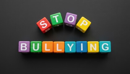 Obraz premium Colorful toy blocks arranged on a dark surface spelling stop bullying with bright letters creating a bold simple scene that delivers a clear message about awareness and safety