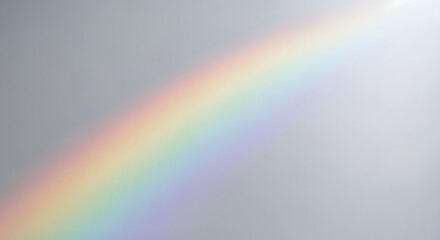 Fototapeta premium A rainbow arc visible against a light gray sky with a bright diffused light source in the background