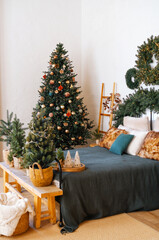Cozy bedroom with decorated Christmas tree and winter wreath overhead