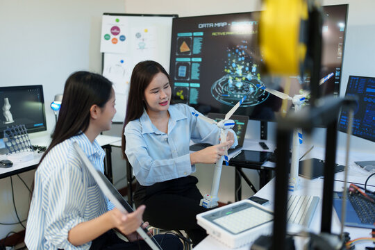 A female engineer is sitting and checking the operation of solar panels and wind turbines in the office. - Powered by Adobe