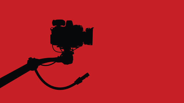 Silhouette of a professional video camera on a jib arm isolated on a red background representing film production and videography