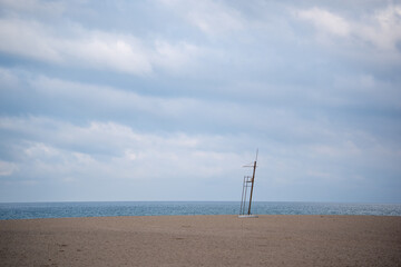 Deserted lifeguard tower standing on vast sandy beach under cloudy sky with calm sea on horizon