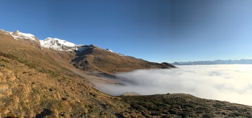 Late Autumn Landscape in the Engadin Swiss Alps with Golden Mountain Slopes, Morning Mist, Deep Blue Alpine Sky and snowcapped mountains 
