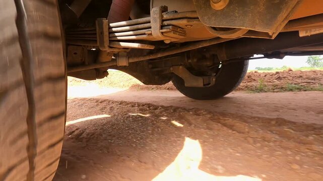ow angle close up of a car tire driving on a dusty gravel road in rural countryside, capturing texture, motion and rugged travel atmosphere for road trip and transportation concepts