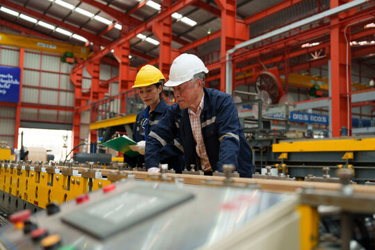 Engineers and staff inspect the production line of components in a metal sheet and metal roofing manufacturing plant.