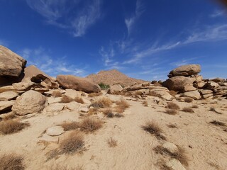  A stunning daytime perspective of the Golden Rock region in Tabuk. The historic red rocks, glistening desert sand, and clear blue skies combine to form a picturesque landscape.
