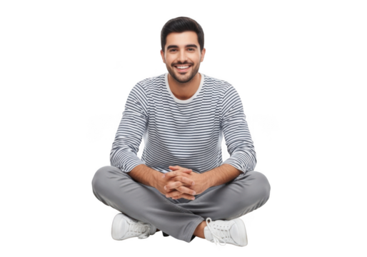 Smiling young man with dark hair and beard wearing a striped long sleeve shirt and grey pants sitting cross legged isolated on transparent background
