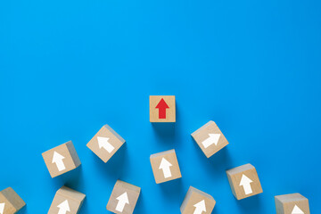 wooden blocks with irregular white arrows and one red arrow pointing right direction isolated on blue background. leadership concept