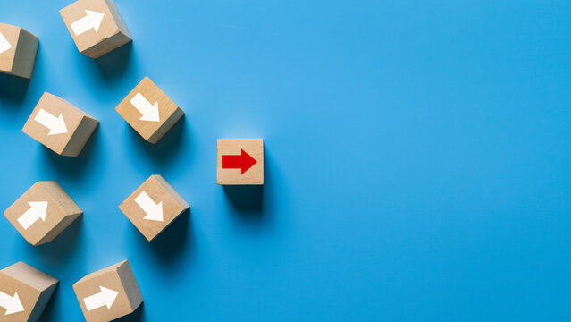 wooden blocks with irregular white arrows and one red arrow pointing right direction isolated on blue background. leadership concept