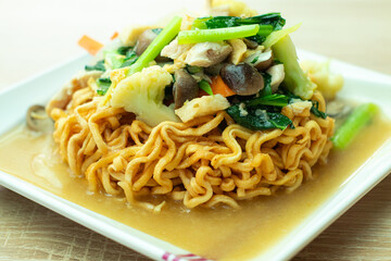 Crispy ifumi noodles topped with savory stir-fried vegetables and chicken in thick gravy, served on a white plate